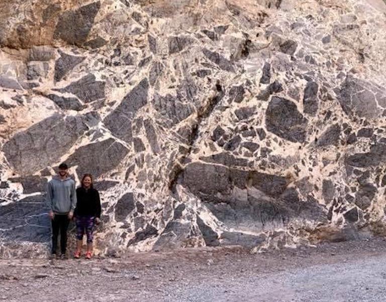 Two students standing by an outcrop of breccia in Titus Canyon