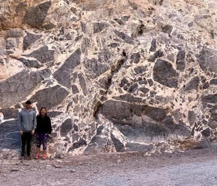 Two students standing by an outcrop of breccia in Titus Canyon