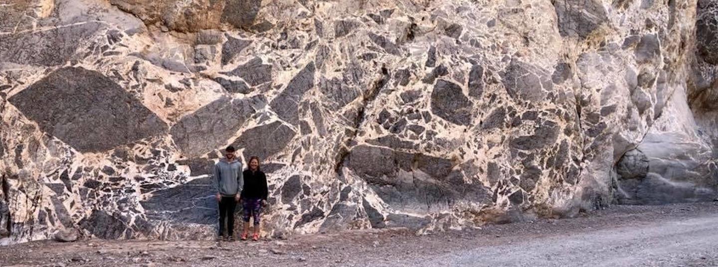 Two students standing by an outcrop of breccia in Titus Canyon