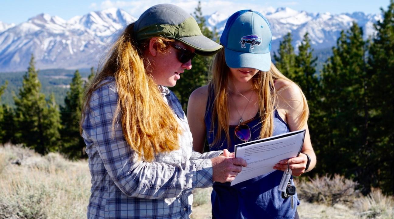 Women reviewing notebook on a mountain