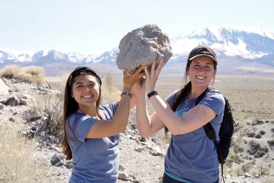 Women lifting big block of pumice