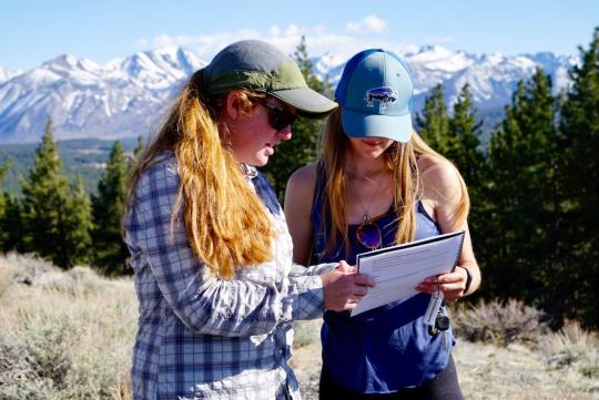 Women reviewing notebook on a mountain